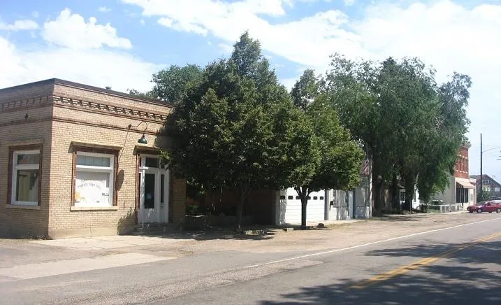 A one-storey brick storefront and shade trees on Main Street in Old Town Timnath